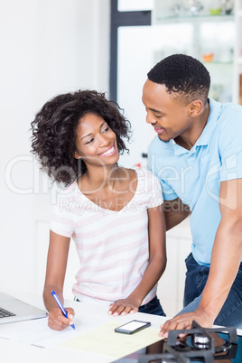 Young couple using laptop while calculating bills