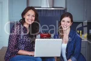 Two beautiful women using a laptop in kitchen