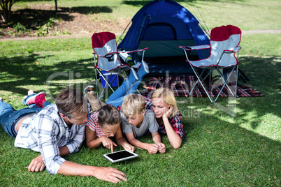 Family lying on grass and using digital tablet