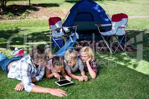 Family lying on grass and using digital tablet