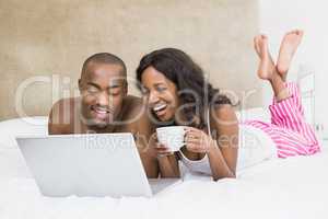 Young man using a laptop and woman holding coffee cup