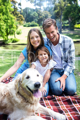 Happy family sitting in the park with their dog