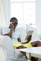 Man looking at digital tablet while talking on phone