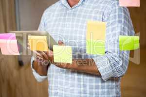 Man holding digital tablet and sticky notes