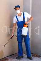 Portrait of worker spraying chemical on wall