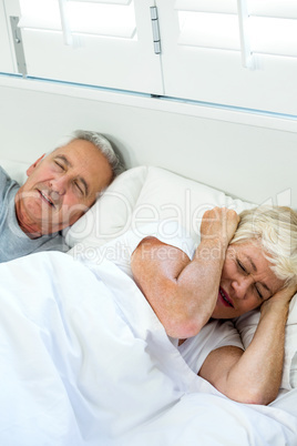 High angle view of irritated senior woman sleeping by snoring ma