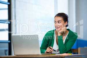 Woman sitting at desk with laptop and graphic tablet