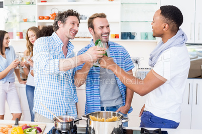 Friends toasting beer and wine glasses in kitchen