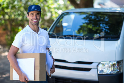 Portrait of smiling delivery person with cardboard box