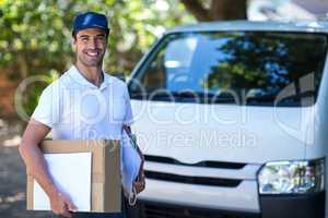 Portrait of smiling delivery person with cardboard box