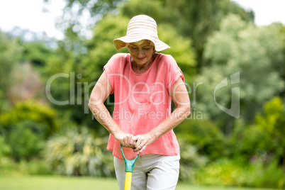 Senior woman standing with rake in yard