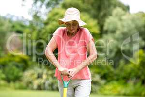 Senior woman standing with rake in yard