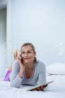 Smiling woman holding digital tablet while talking on phone on b