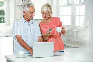 Senior couple with credit card while using laptop