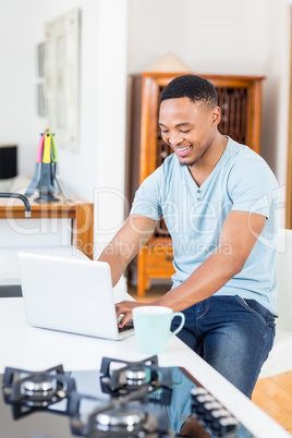 Young man using laptop in kitchen