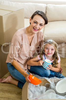 Mother and daughter unpacking box in new house