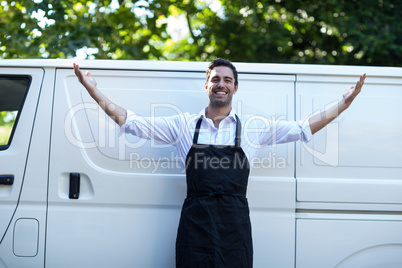 Portrait of confident delivery man with arms outstretched