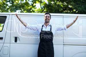 Portrait of confident delivery man with arms outstretched