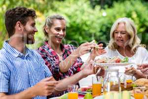 Couple with grandmother having sandwich at yard