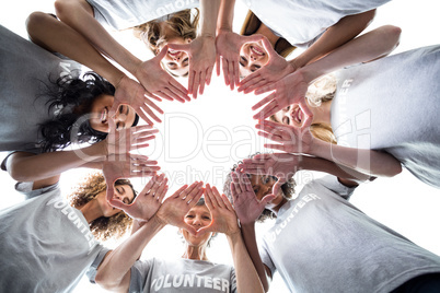 Happy volunteers standing in a circle with their hands together