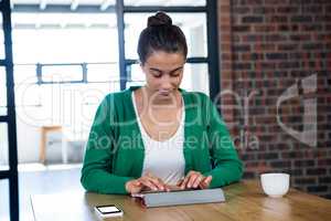 Woman using digital tablet with mobile phone and coffee cup on t