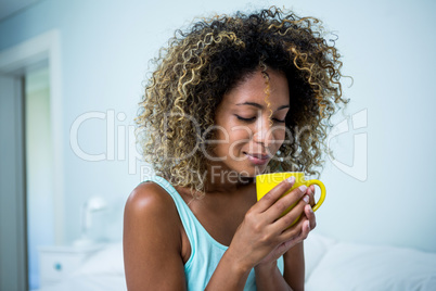 Young woman drinking a coffee on bed