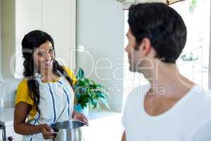 Happy couple talking while preparing food in kitchen