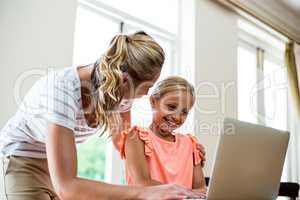 Mother with daughter using laptop at table