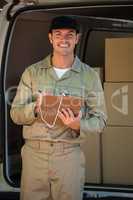 Happy delivery man writing on a clipboard