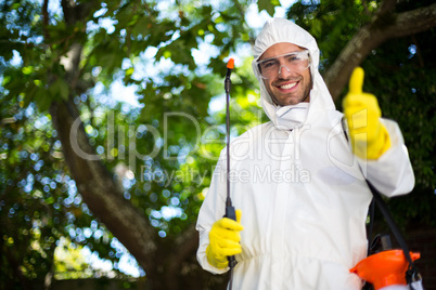 Smiling man showing thumbs up while holding insecticide