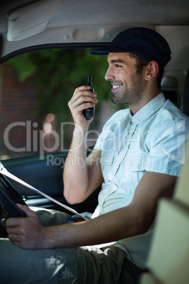 Smiling delivery man using walkie-talkie