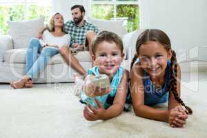 Happy siblings watching tv against parents relaxing at home