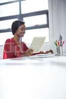 Woman using laptop and holding digital tablet