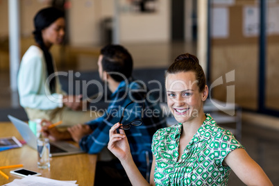 Young woman holding spectacles smiling at camera