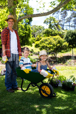 Father carrying his son and daughter in a wheelbarrow