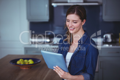 Beautiful woman using digital tablet in kitchen