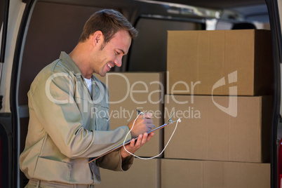 Happy delivery man writing on a clipboard