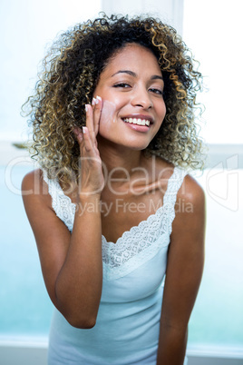 Young woman applying moisturizer