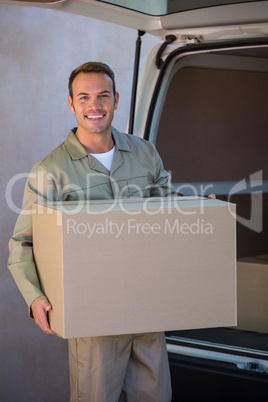 Happy delivery man carrying a cardboard box