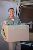 Happy delivery man carrying a cardboard box