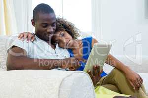 Young couple using a digital tablet in living room