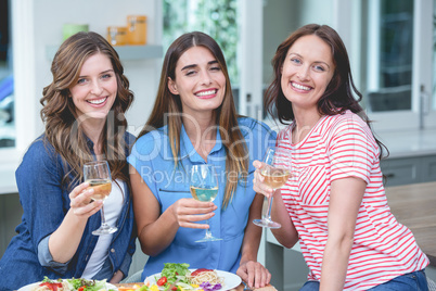 Friends holding glass of wine while having meal