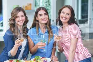 Friends holding glass of wine while having meal