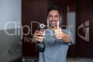 Smiling man showing thumbs up while holding cordless hand drill