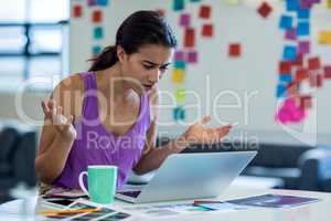 Young woman looking surprised while using the laptop