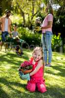 Smiling girl holding flower pot in yard