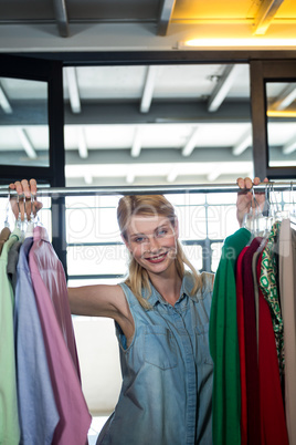 Portrait of a happy woman on clothes display stand