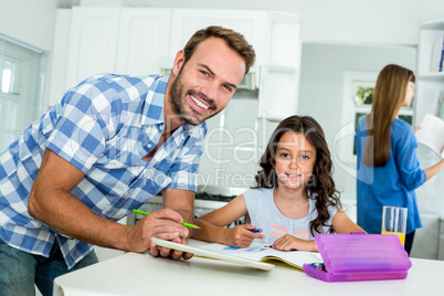 Happy father assisting girl in homework at home