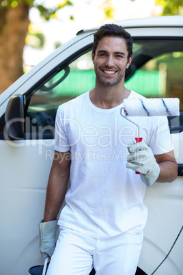 Portrait of confident painter holding equipment