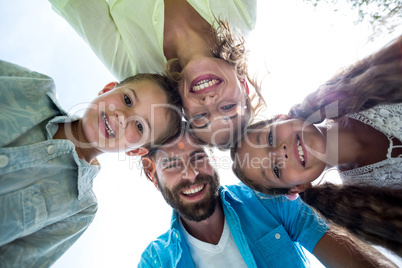 Smiling family forming huddle against sky